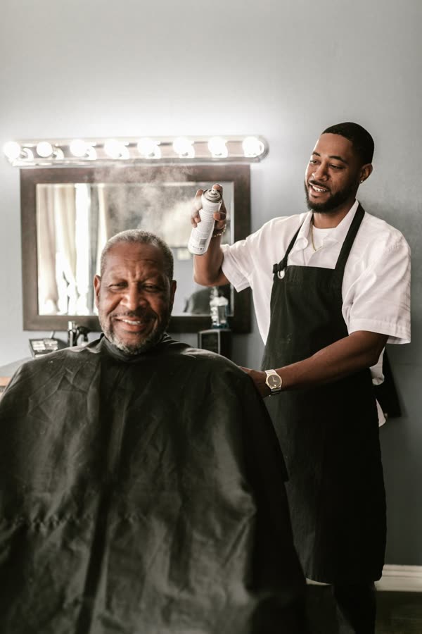 Smiling barber giving a haircut to a happy client in a modern barbershop